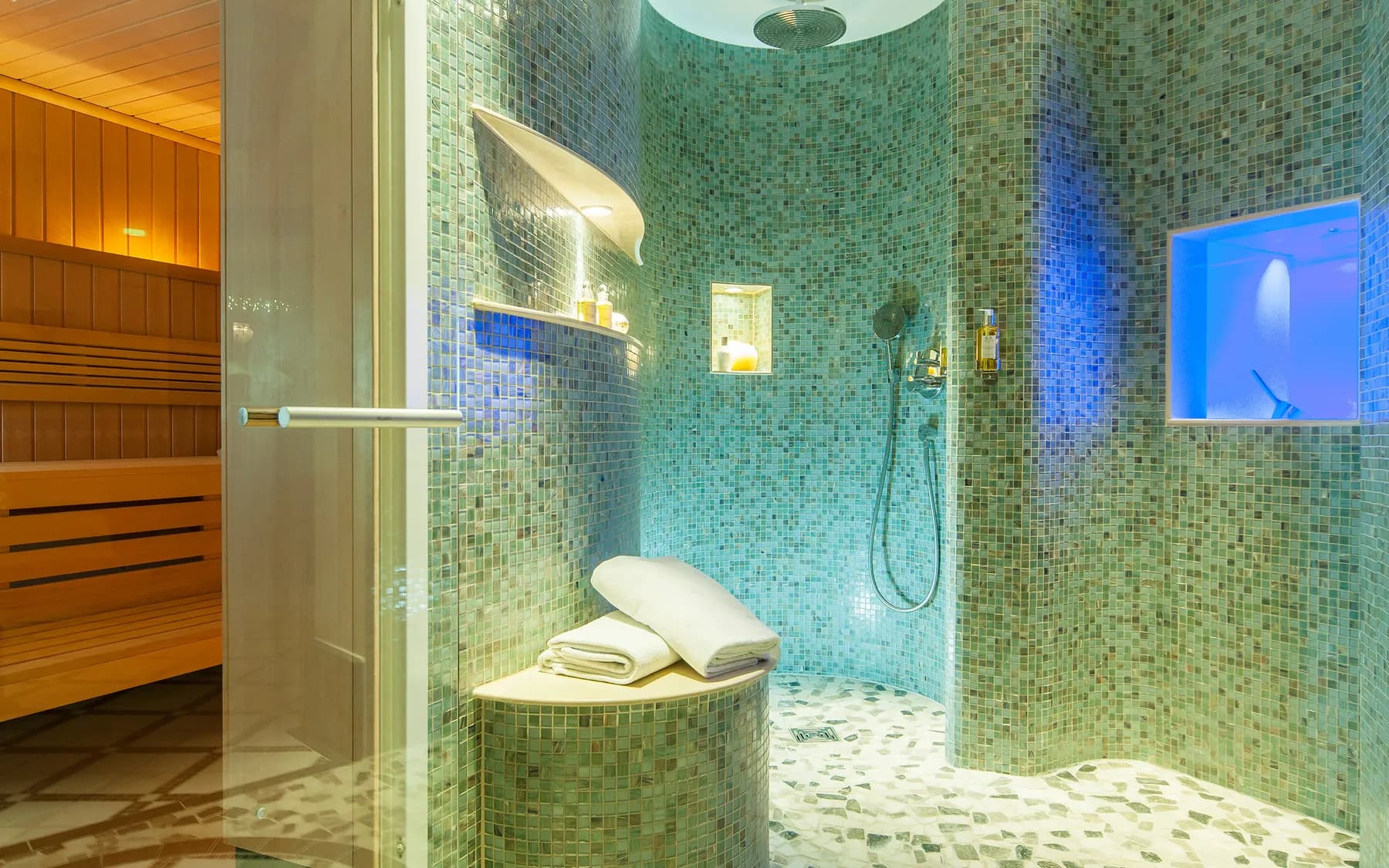 Spa corner with a mosaic shower and a sauna glass door