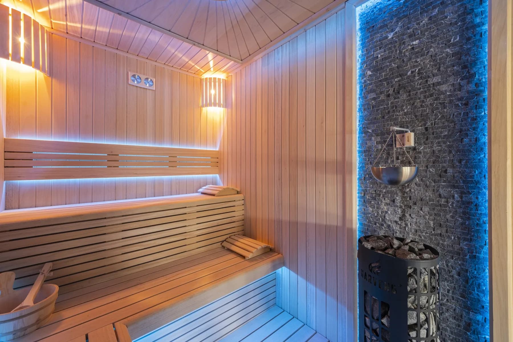 Sauna mit Steinwand und beleuchteten Bänken