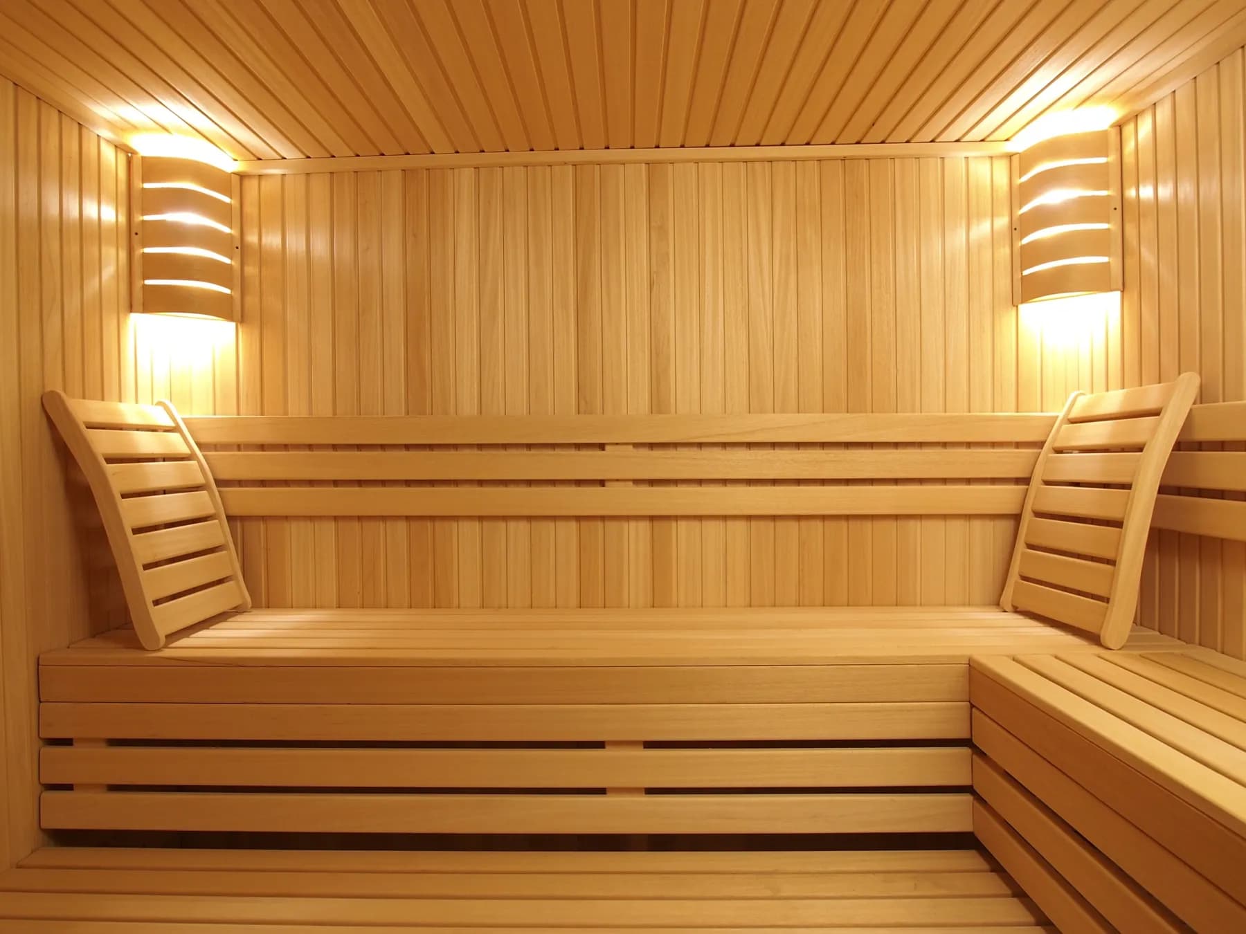 Sauna en bois clair avec banquettes éclairées et appliques